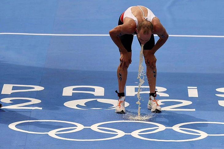 O triatleta Tyler Mislawchuk, da delagação canadense, vomita após prova de triatlo masculino no rio Sena